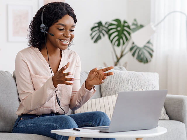 A lady wearing a headset looking at a laptop