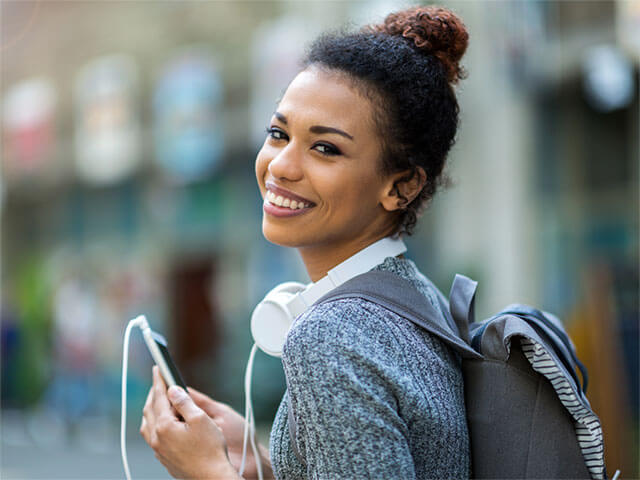 A lady wearing a rucksack with headphones around her neck