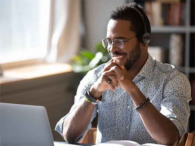 A man wearing headphones and looking at a laptop